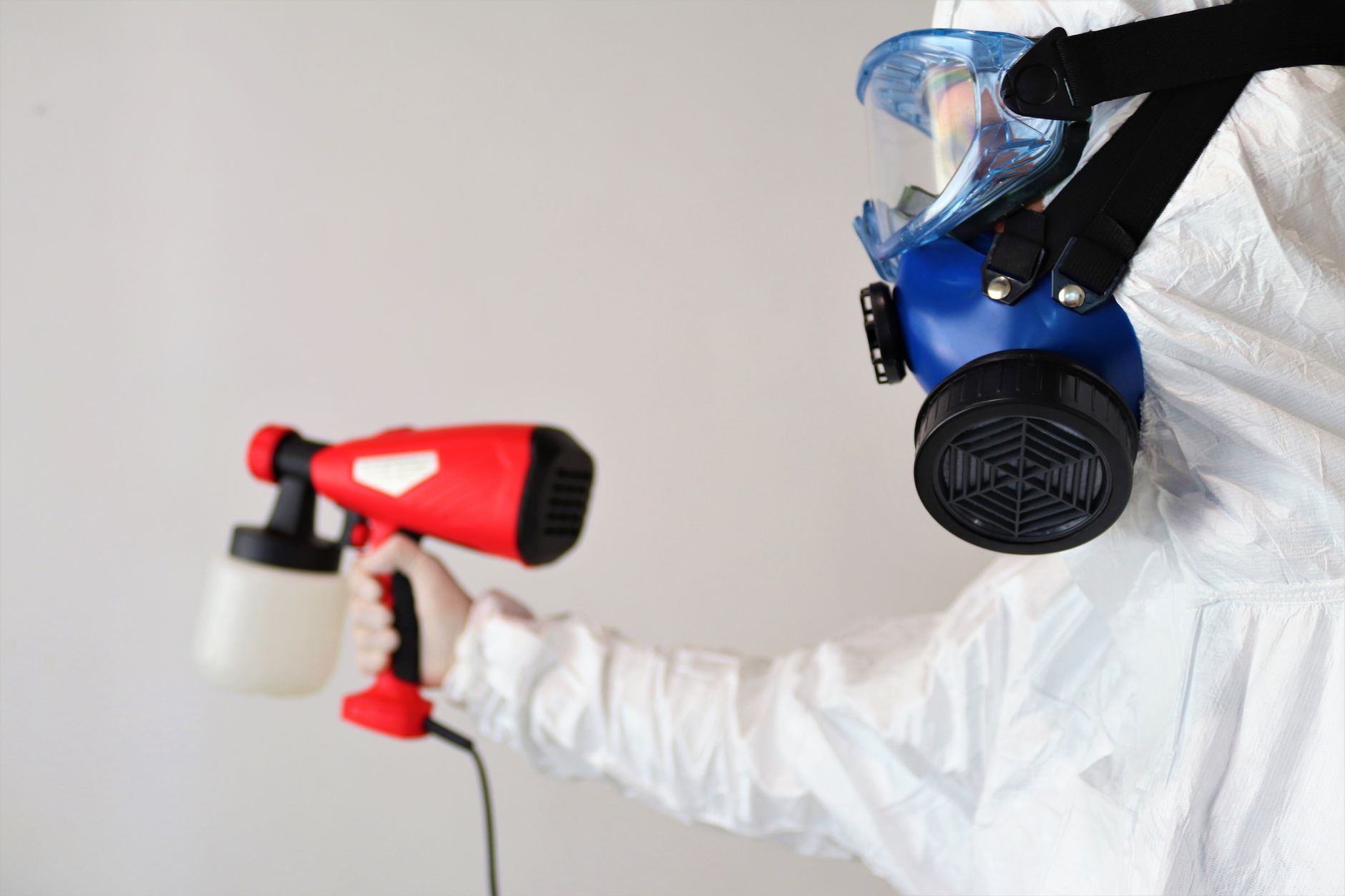 A certified mold remediation technician wearing PPE and using a thermal imaging camera to detect hidden moisture behind a wall in a residential property in Indian Creek, Texas.
